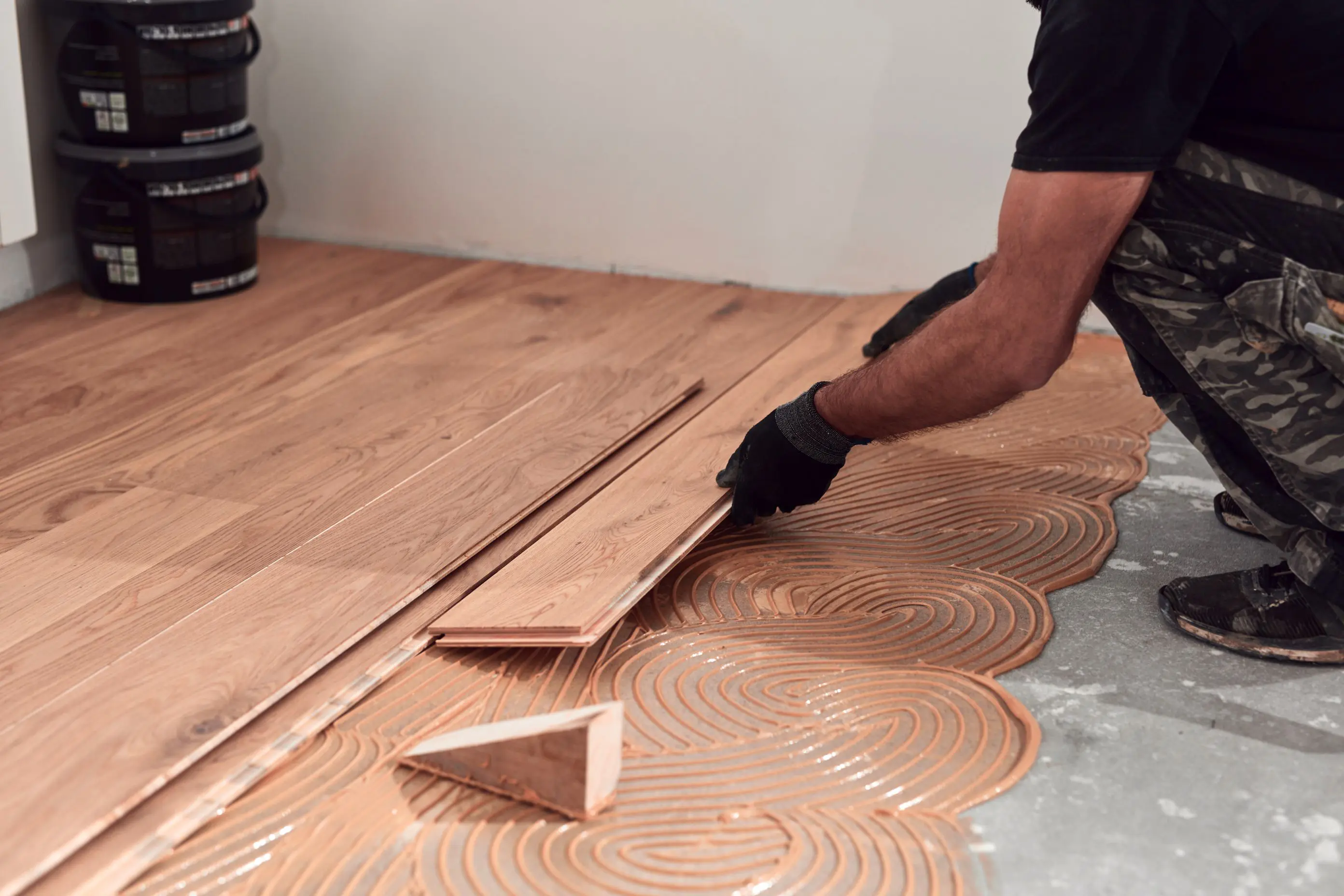 Installing wooden floor with adhesive glue.